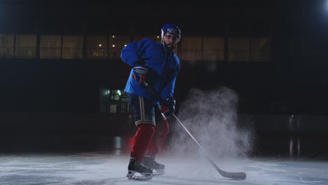 Un-Jugador-De-Hockey-Con-Uniforme-De-Hockey-Sale-De-La-Oscuridad-Con-Un-Palo-En-Las-Manos-Y-Mira-Directamente-A-La-Cámara
